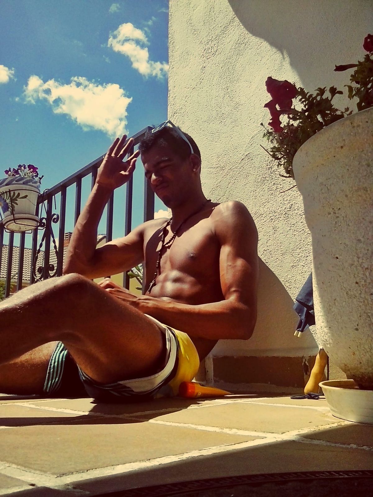 Manu sentado al sol en una terraza, saludando, con el primer cambio ya visible