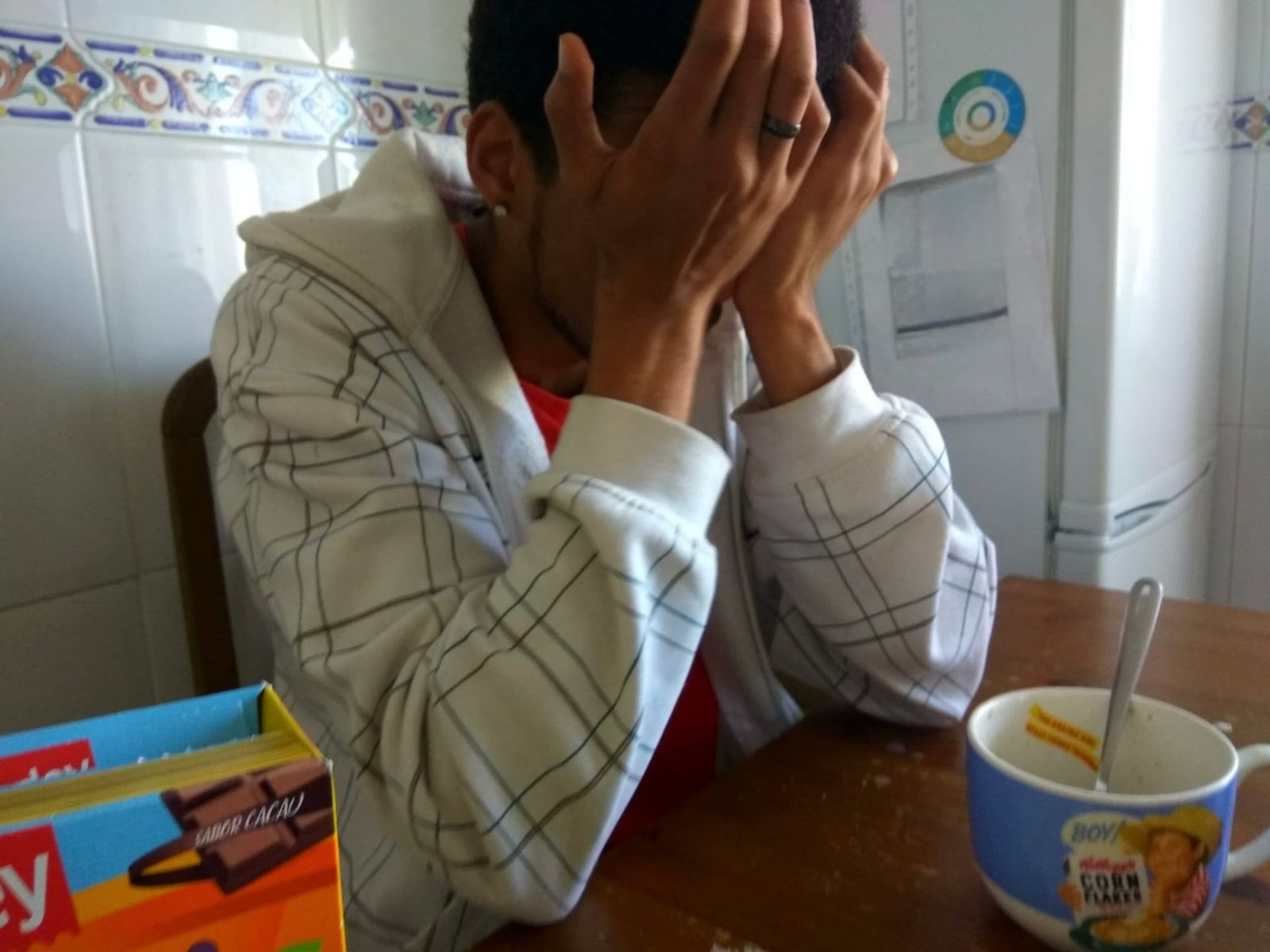 Manu sentado en la cocina con la cara entre las manos y un cuenco de cereales delante, frustrado